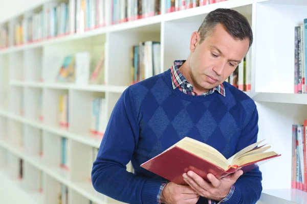 Man stond lezen in de bibliotheek — Stockfoto