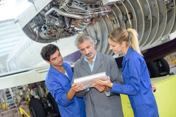 Estudantes ao lado de aeronaves olhando para manual — Fotografia de Stock