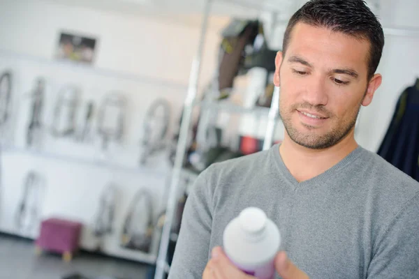 Man looking at equestrian product in plastic bottle — Stock Photo, Image