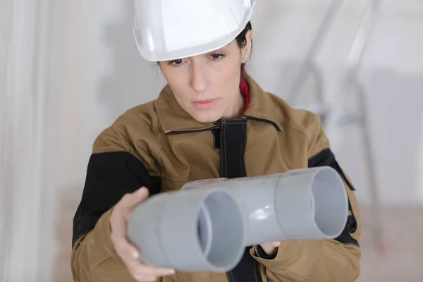 Жінка-будівельник перевіряє пластикові труби — стокове фото