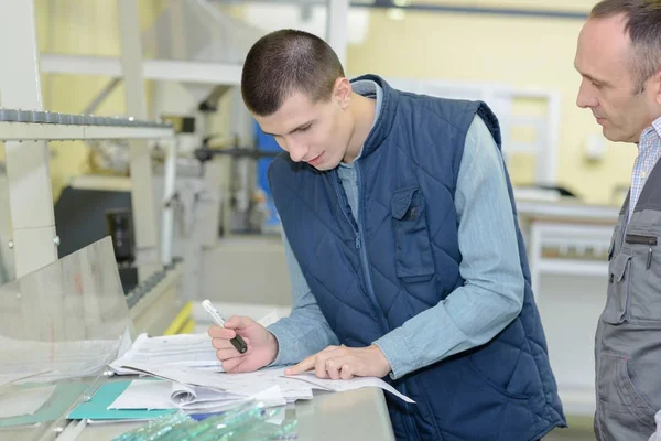 Ingenieur toont trainee plannen met cmm arm op de voorgrond — Stockfoto