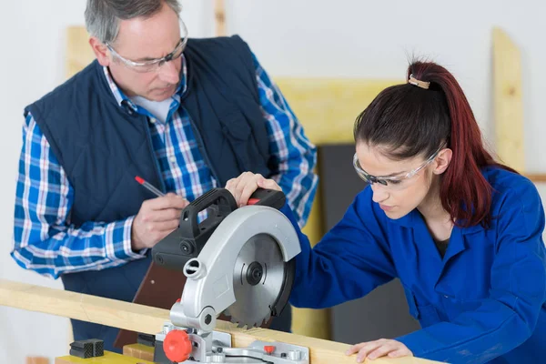 Carpinteiro com aprendiz do sexo feminino trabalhando no canteiro de obras — Fotografia de Stock