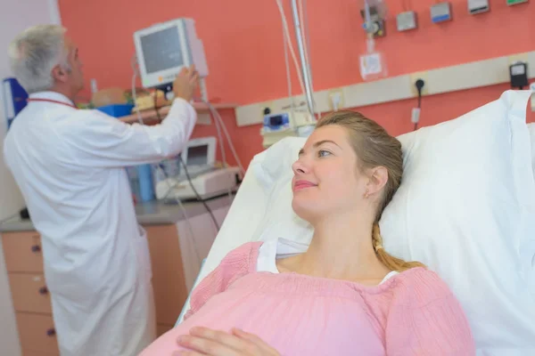 Vacker ung gravid kvinna sitter i en sjukhussäng — Stockfoto