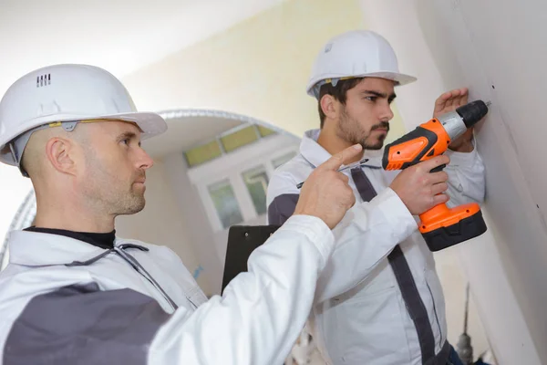 Trabajadores de la construcción perforando un muro de hormigón — Foto de Stock