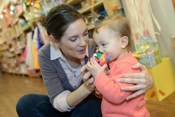 Moeder en dochter met aantrekkelijke leverancier in de speelgoedwinkel — Stockfoto