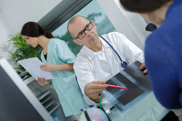 Medico che mostra i raggi X al suo paziente nello studio medico — Foto Stock