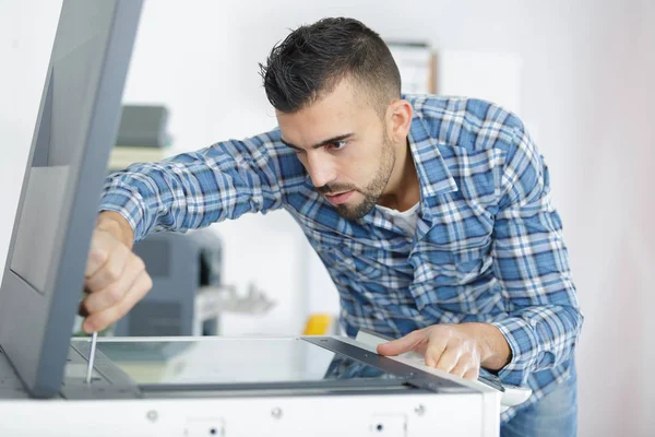 Homem reparando fotocopiadora usando chave de fenda — Fotografia de Stock