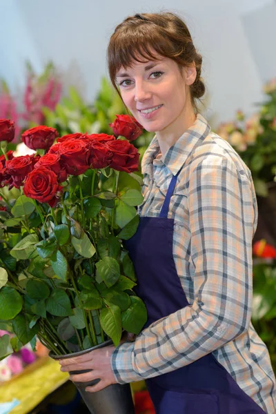 Retrato de florista femenina sosteniendo rosas rojas — Foto de Stock