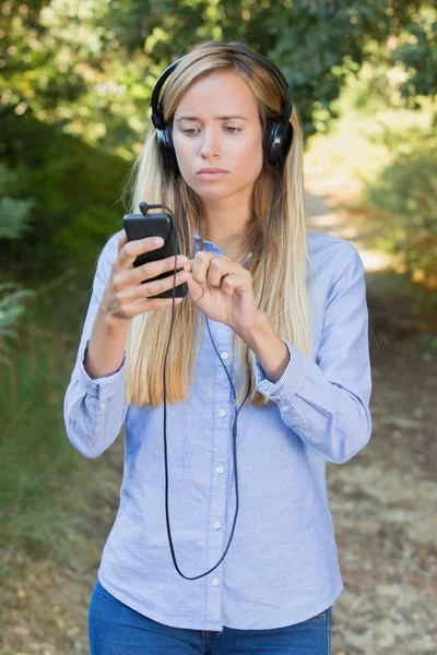 Hermosa joven mujer volver a insertar sus auriculares durante el paseo —  Fotos de Stock