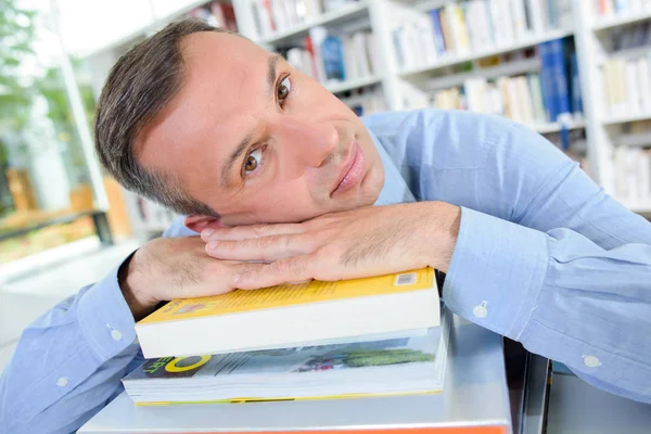 Hombre apoyando su cabeza en un montón de libros —  Fotos de Stock