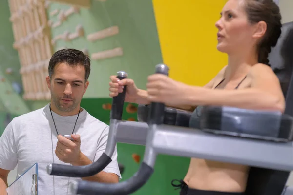 Jeune femme exécuter l'exercice dans la salle de gym motivée par l'entraîneur — Photo