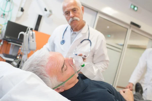 Médico examinando seu paciente usando máscara de oxigênio — Fotografia de Stock