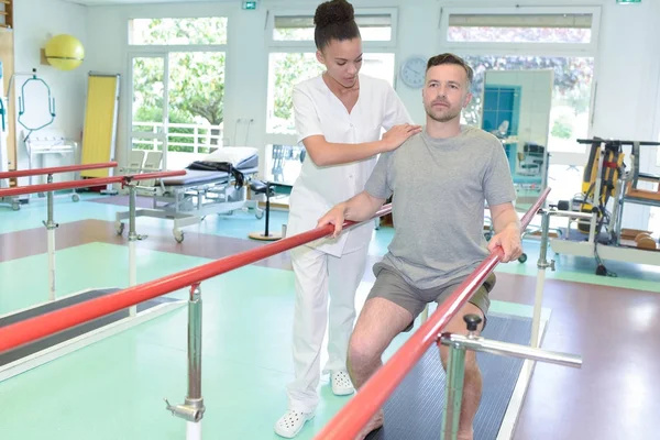 Enfermera que asiste al hombre en el ejercicio de piernas —  Fotos de Stock