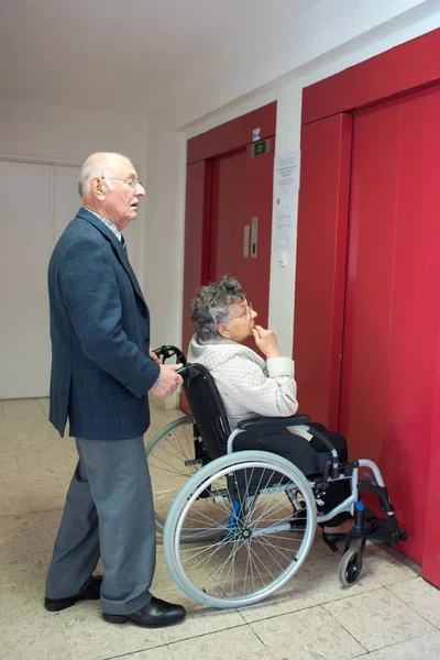 Esposo y esposa en silla de ruedas saliendo del ascensor de pasajeros — Foto de Stock