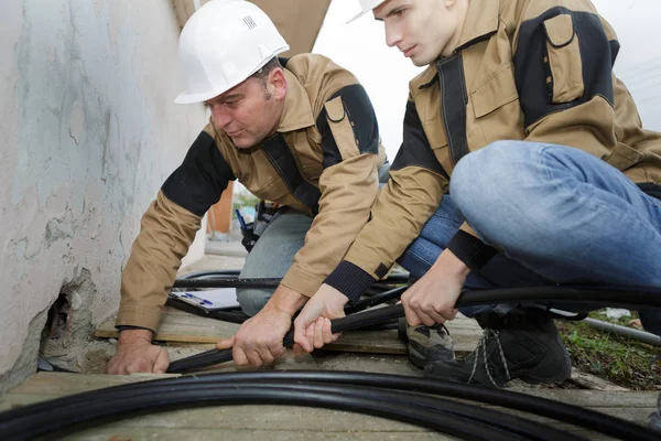 Two plumbers fixing sewerage pipe at construction site — Stock Photo, Image