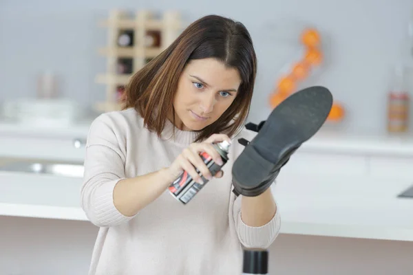 Женщина распыляет обувь и спрей — стоковое фото