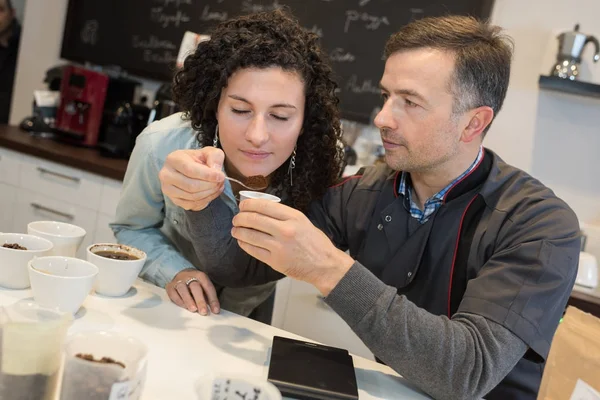Lehrling riecht Kaffeebohnen in Werkstatt — Stockfoto