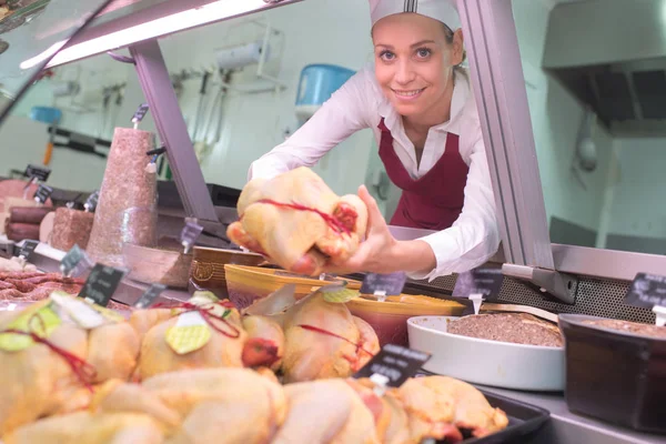 Vrouwelijke slager bedrijf rauwe kip — Stockfoto