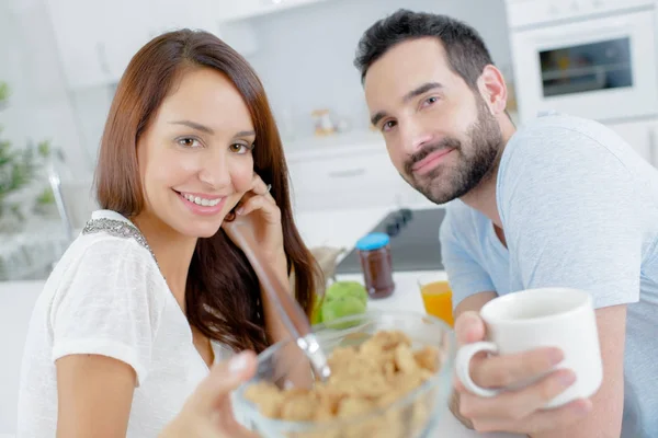Jovem casal feliz tomando café da manhã junto com frutas e suco — Fotografia de Stock