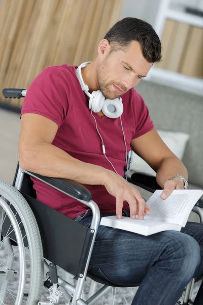 Engelli adam tekerlekli sandalyeye mahkum bir kitap okuma — Stok fotoğraf