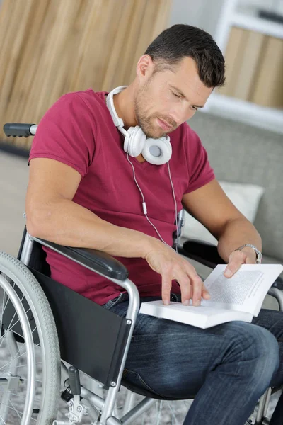 Hombre discapacitado en silla de ruedas leyendo un libro — Foto de Stock