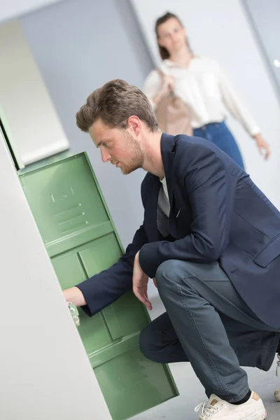 Joven estudiante masculino abriendo su casillero en la universidad — Foto de Stock