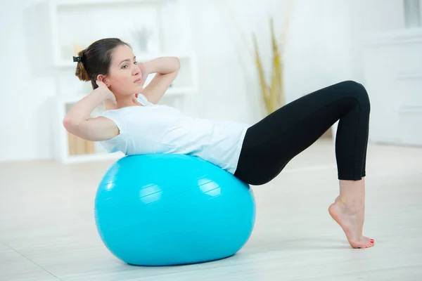 Молодая женщина упражняется с помощью гимнастического мяча — стоковое фото