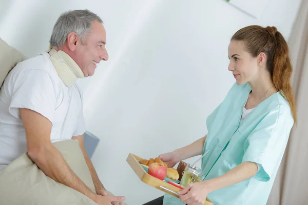 看護師は患者に彼の食事を与える — ストック写真