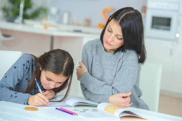 Giovane ragazza che scrive in un libro con sua madre — Foto Stock