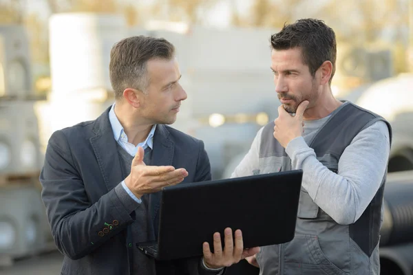 Manager and worker talking outside and using a laptop — Stock Photo, Image