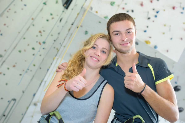 Jovem casal dando polegares para cima na frente da parede de escalada — Fotografia de Stock