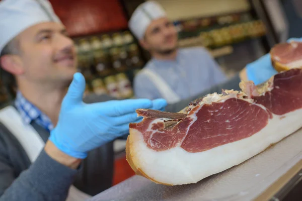 Butcher suggesting cured ham — Stock Photo, Image