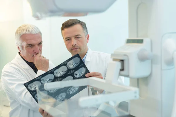 Два молоді лікарі, які вивчають рентгенівську плівку в діафаноскопі — стокове фото