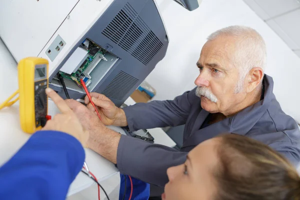 Vrouw met behulp van een multimeter tijdens elektriciteit les — Stockfoto