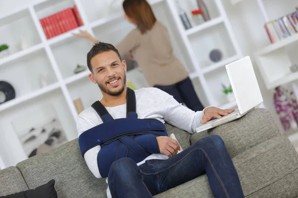 Homem com a perna ferida relaxando no sofá — Fotografia de Stock