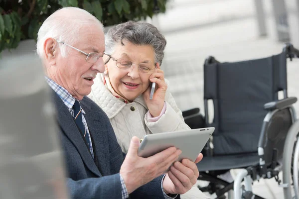 Coppia anziana godendo di tecnologia moderna utilizzando tablet e cellulare — Foto Stock