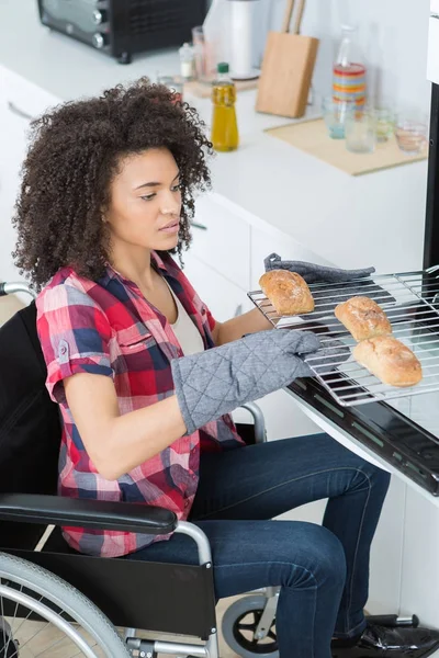 Woman in wheelchair baking in oven — Stock Photo, Image