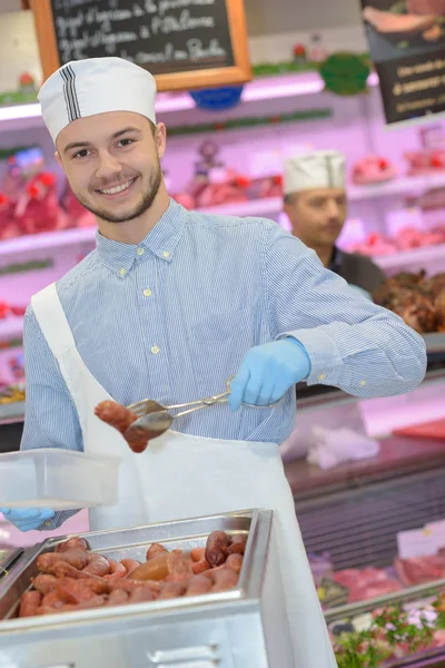 Butcher teaching a young one how to sell meat — Stock Photo, Image