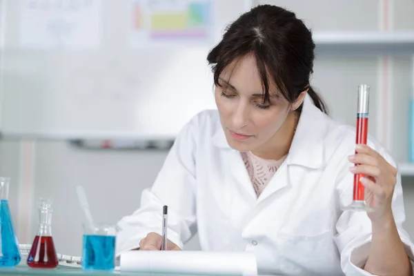 Mujer científica mantiene en mano el tubo de ensayo en laboratorio — Foto de Stock