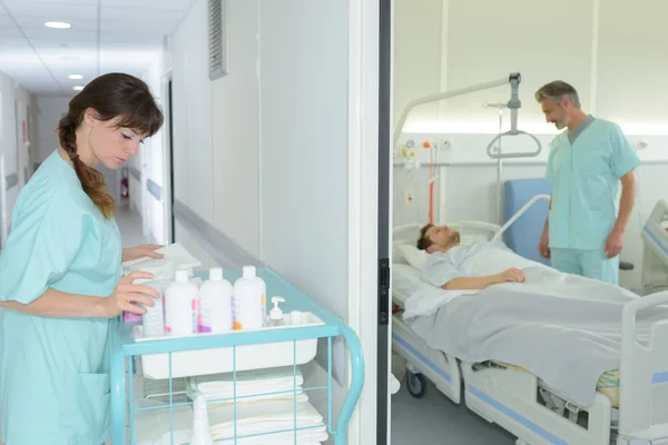Krankenschwester wählt Produkte aus Einkaufswagen im Krankenhausflur — Stockfoto