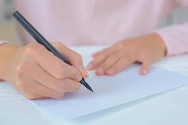 Junge Frau schreibt auf ein Blatt Papier — Stockfoto