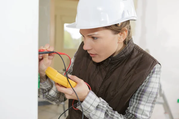 Female electrician testing a wall socket — Stock Photo, Image