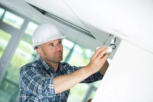 Male technician installing camera on wall with screwdriver — Stock Photo, Image