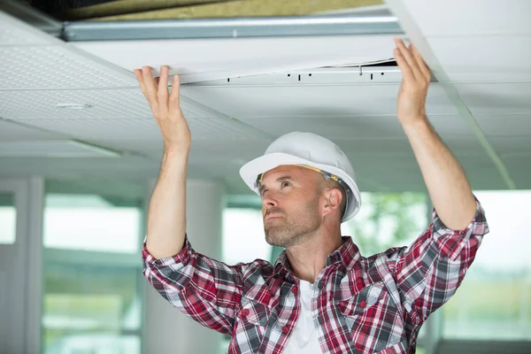 Человек устанавливает подвесные потолки в доме — стоковое фото