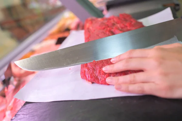 Butcher cuts meat and cutting — Stock Photo, Image