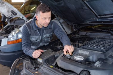 mechanic unscrewing the oil tank in auto repair clipart