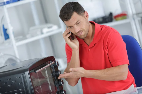 Man efterlyser stöd för att reparera elektrisk apparat — Stockfoto