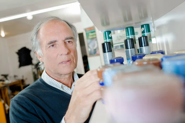 Man looking for a product in the shelf — Stock Photo, Image