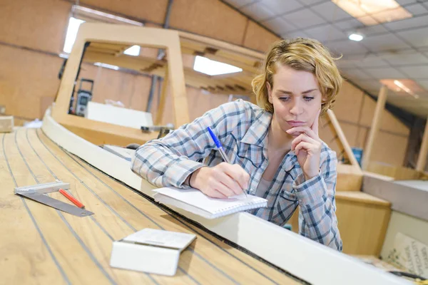 Fundersam kvinnliga industriarbetare som arbetar med plankor — Stockfoto