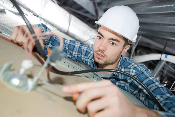 Electrician wiring cables in building ceiling — Stock Photo, Image